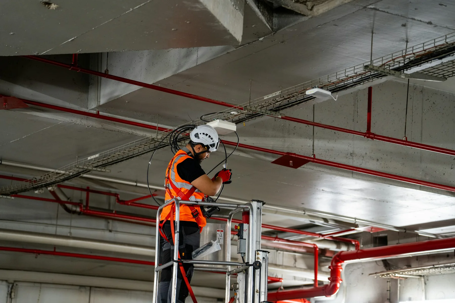 An engineer on a lift platform working on the services in a building ceiling