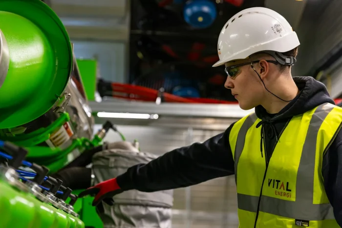 An engineer in a high-visibility vest working on plant equipment