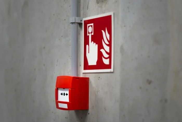 A fire alarm call point and fire action sign on a concrete wall